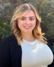 A photo of Charlotte Rooks wearing a white top and black blazer outside.